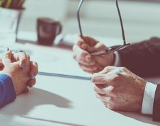 Two people sitting at desk in conversation 