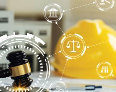 Gavel with illustration of symbols over it, hard hat in back/Adobe Stock