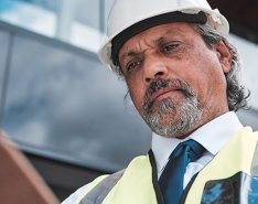 Man in hard hat and vest looking at clipboard