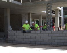 Workers in green shirts and hard hats working on wall